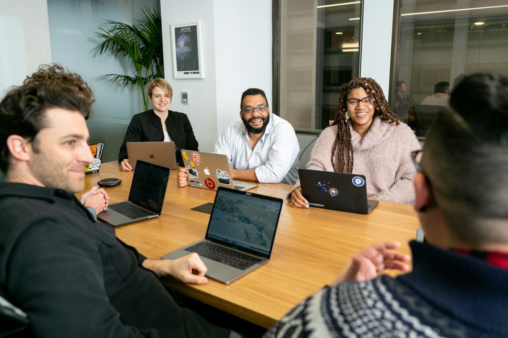 SEO team discussing a client campaign around a meeting table with laptops